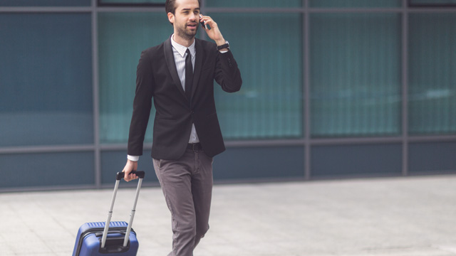 Man walking with a suitcase when talking in mobile