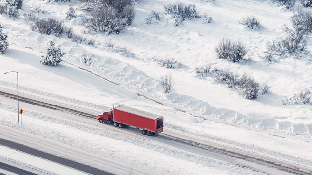 Red truck driving on snowy roads