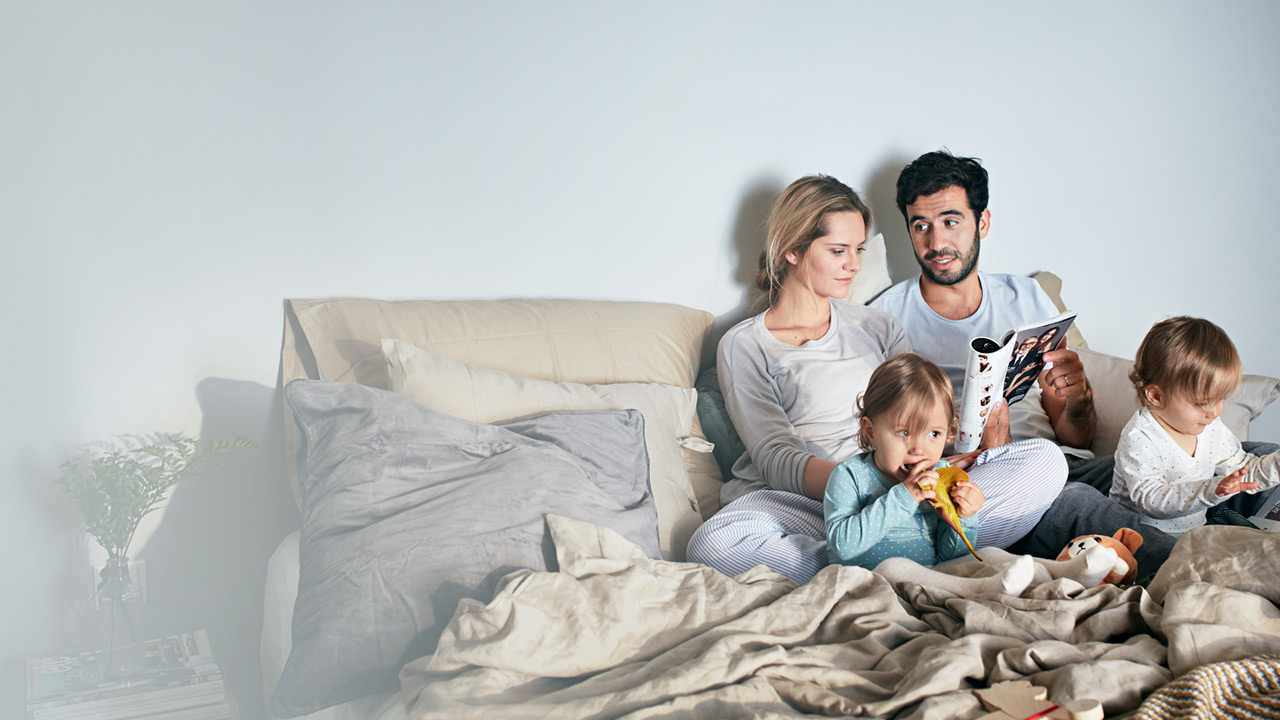Couple talking together in the bed with a small kid.