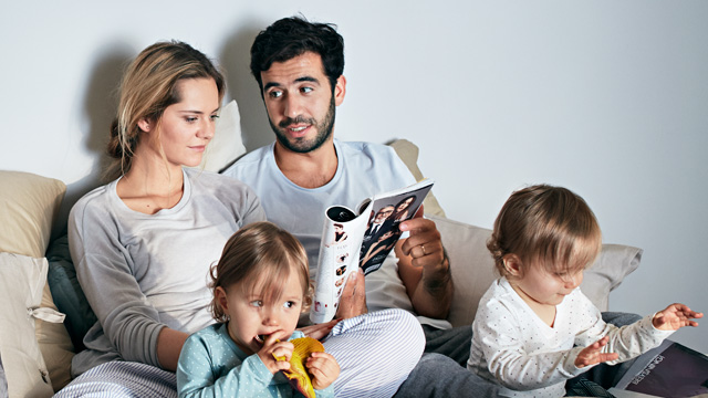 Couple talking together in the bed with small kids.