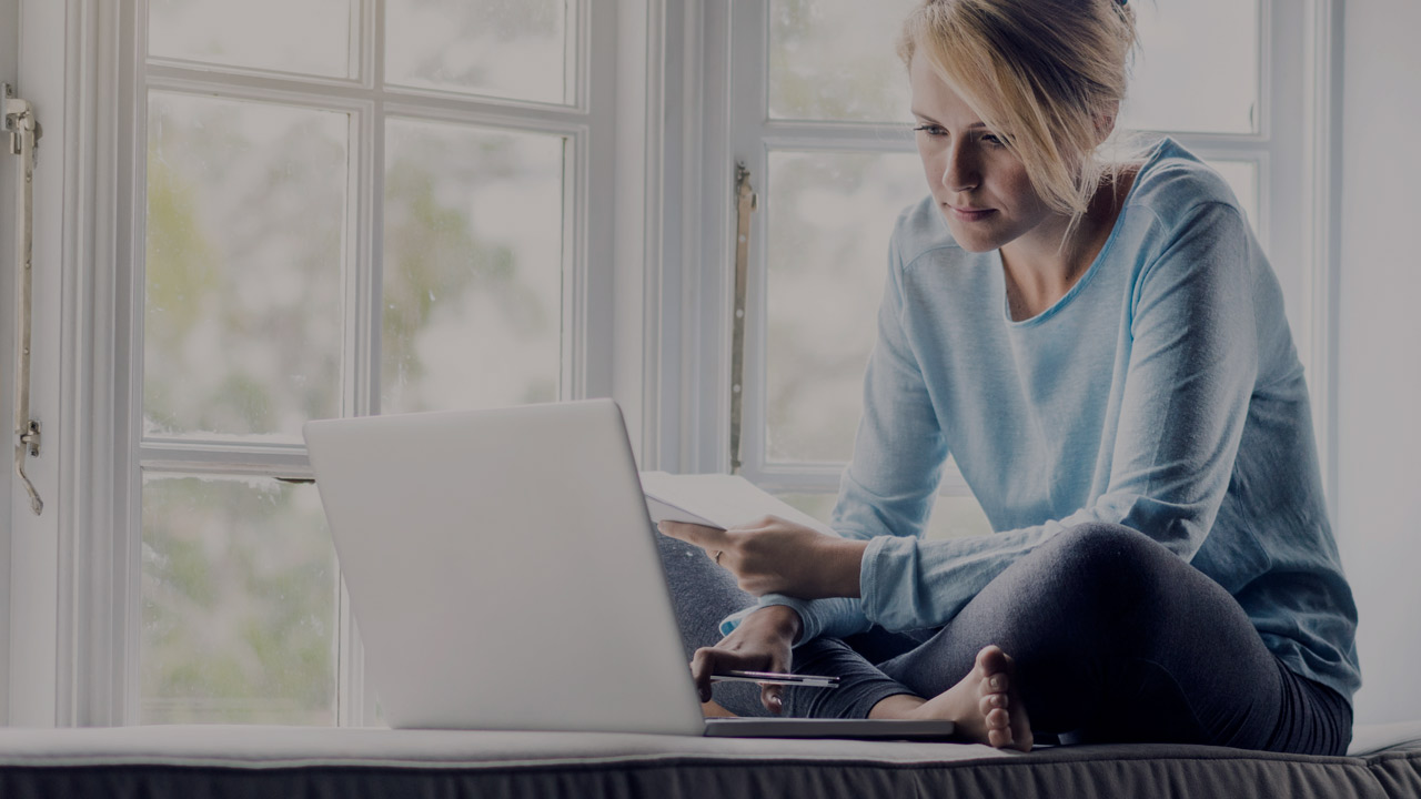 Kvinne hjemme med laptop i sofa