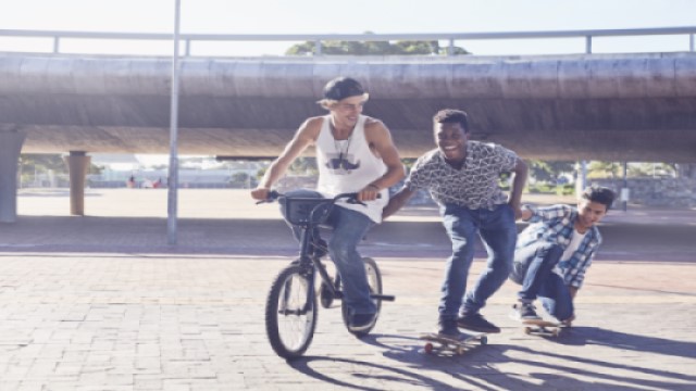 Boys riding bicycle and skateboarding