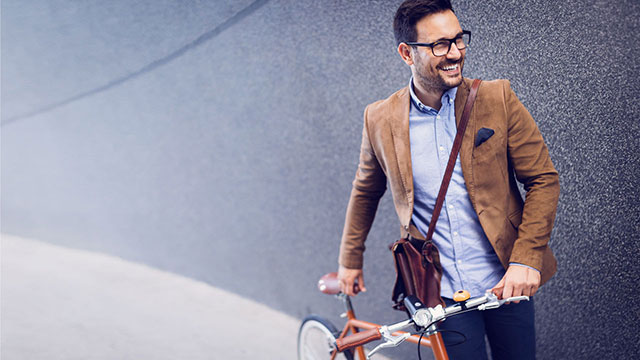 Kuvituskuva, jossa iloinen mies taluttaa polkupyörää graniittisen seinän edessä.