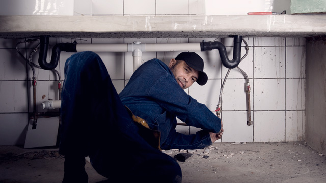 Men in blue clothes renovate kitchen sink