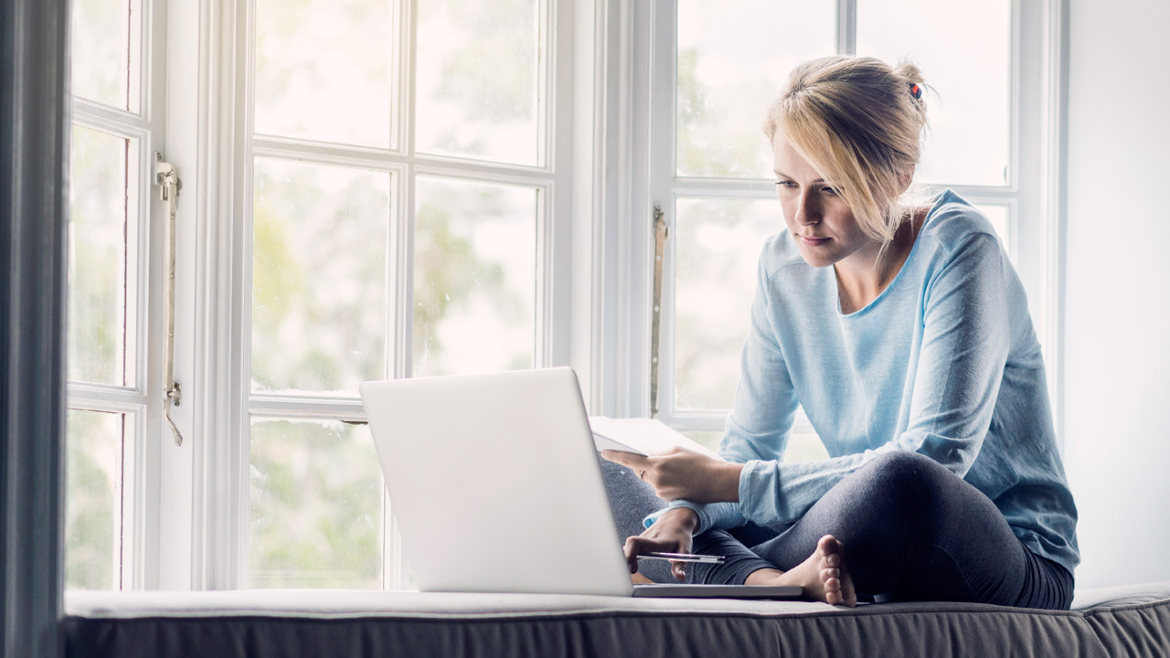 Woman sitting by her window working with her computer