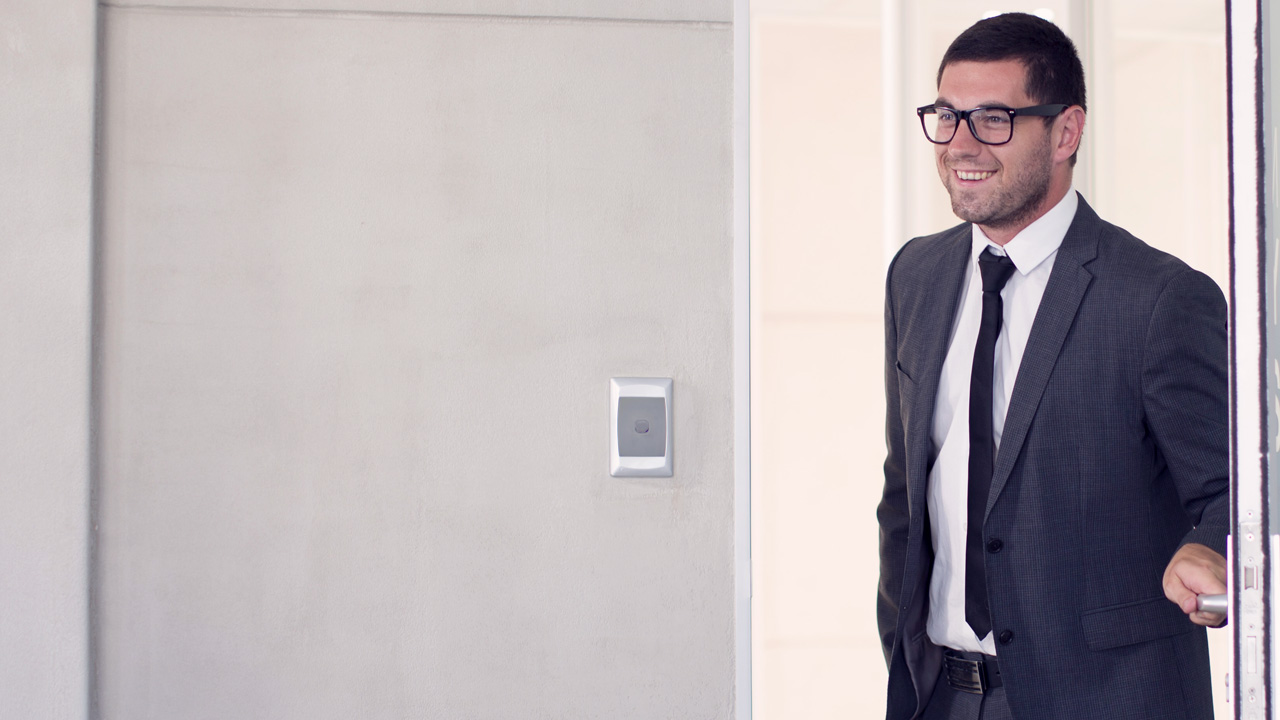 Man in suit entering an office while smiling