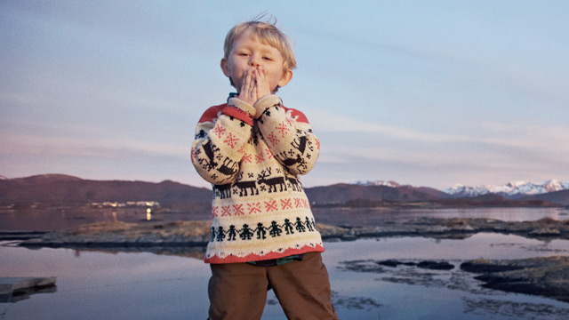 A kid is air kissing outside summertime. 
