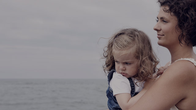 Mother holding daughter on the beach.