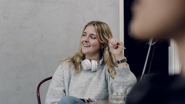 Nainen istuu sohvalla ja pöydällä on tietokone.