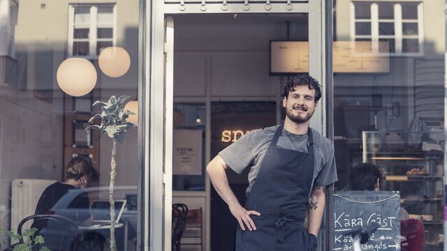 Frontpage - Smiling male entrepreneur standing at cafe SMALL