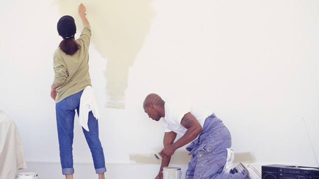 A couple painting a big wall inside