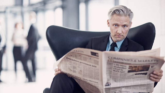 Man reading newspaper in chair