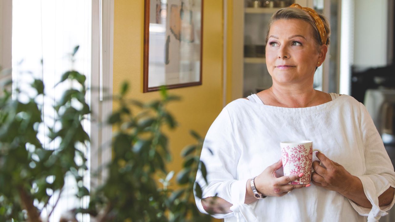 Niina hymyilee ja katsoo kaukaisuuteen kahvikuppi kädessä.